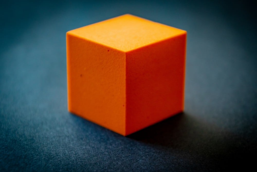 single orange cube block on blue background