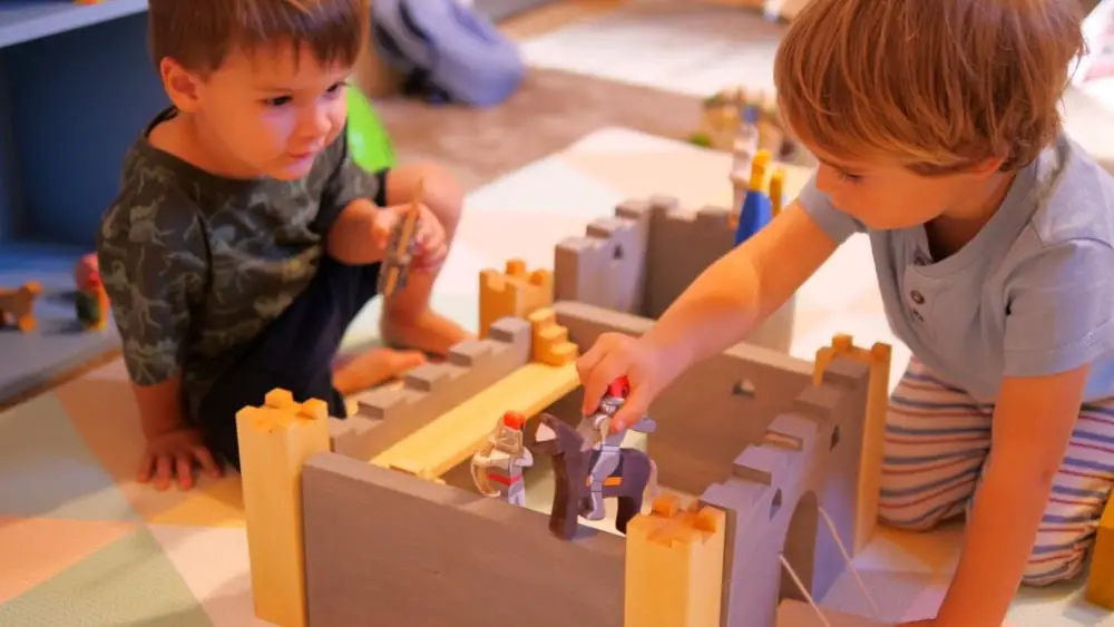 Two children playing with Vulps Toys brand handmade toy figurines and wooden castle.