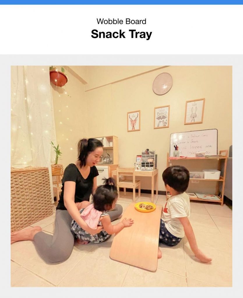 Mom And Her Toddlers Eating Snacks On Wooden Rocking Board